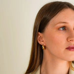 A woman wearing the Amaya Earrings while looking right