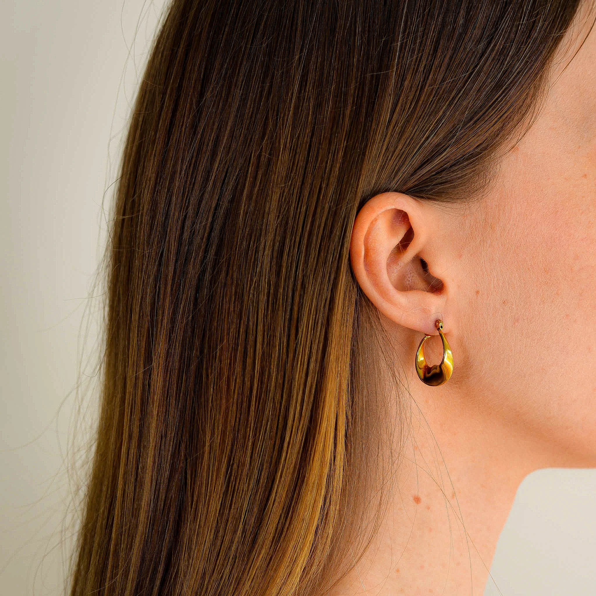 A woman wearing Aria earrings looking right