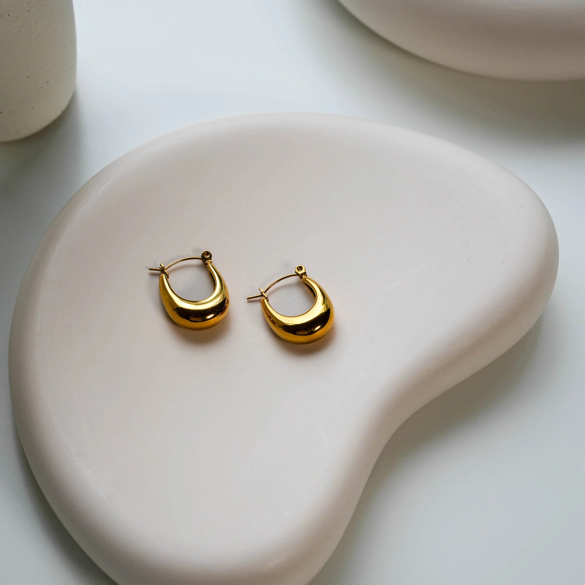 The Leona 18k gold plated earrings on a white plate