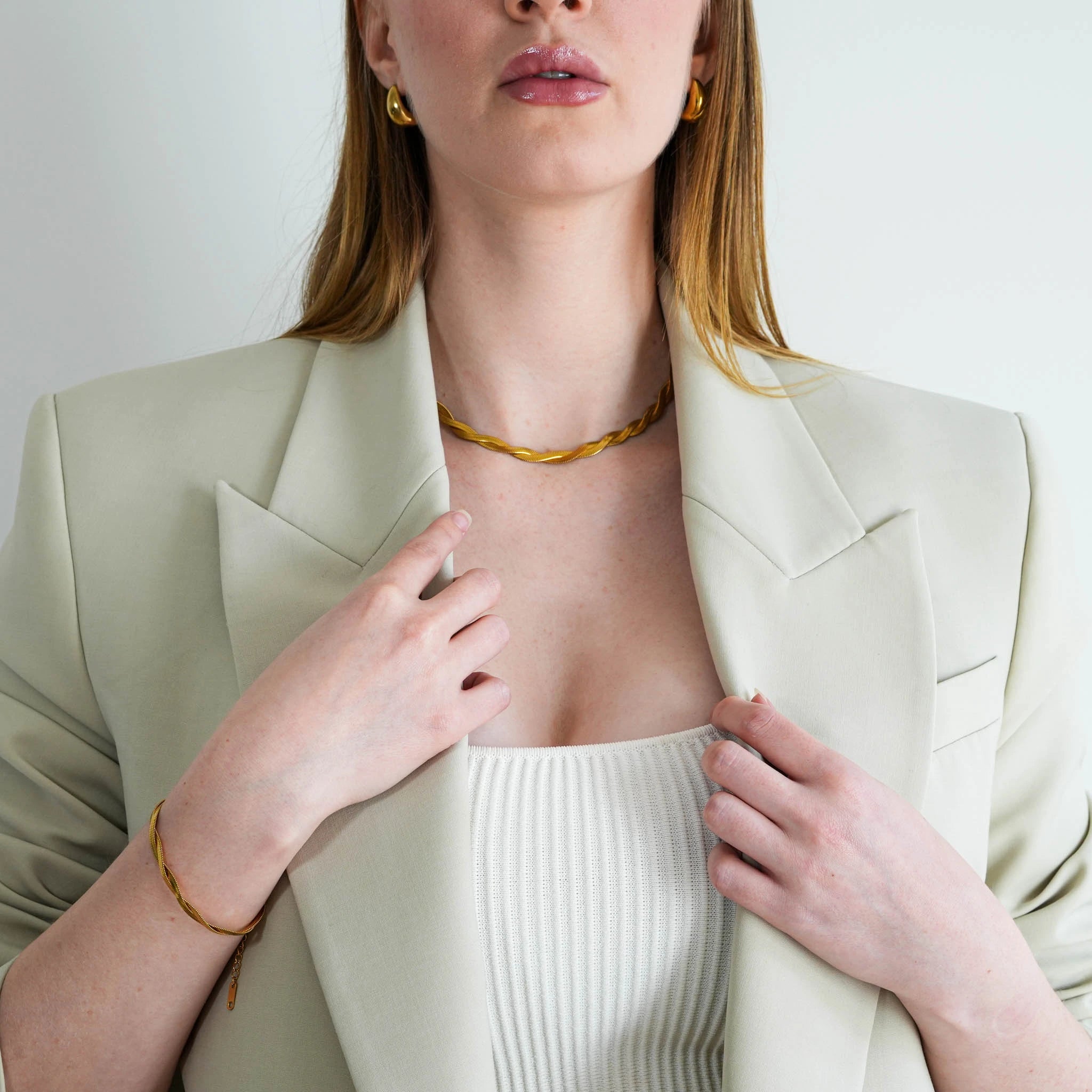 A woman wearing the 18k gold plated Selene bracelet with hands on her jacket